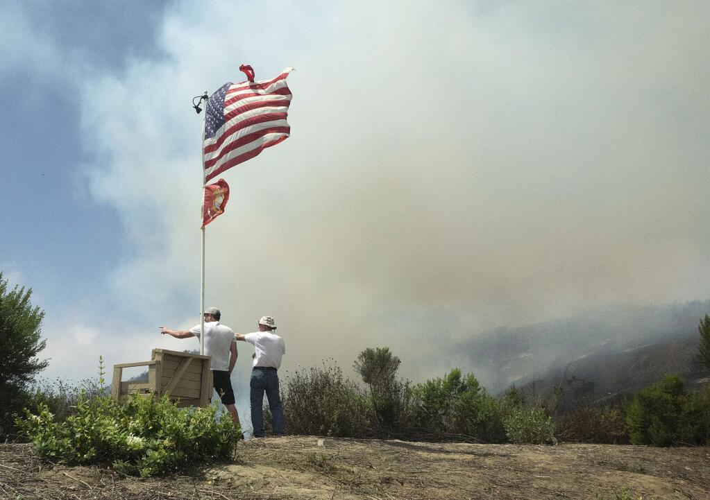 Travis Blake, left, and Paul Turney watch as firefighters set back fires as to put out a brush fire in San Clemente, Calif., Thursday, June 29, 2017. U.S. Sen. Dianne Feinstein says California's wildfire season could be more severe than last year, with nearly 30,000 acres already burned. (Ken Steinhardt/The Orange County Register via AP)