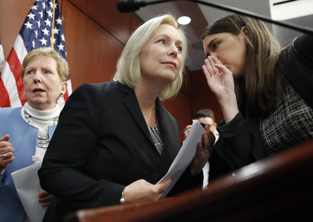 Sen. Kirsten Gillibrand, D-N.Y., center, listens to a staffer before answering questions at a news conference, Tuesday, Dec. 12, 2017, on Capitol Hill in Washington. Gillibrand says President Donald Trump's latest tweet about her was a “sexist smear” aimed at silencing her voice. (AP Photo/Jacquelyn Martin)