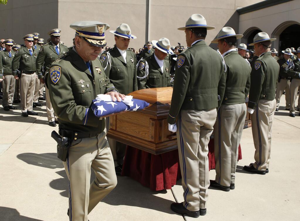 California Highway Patrol Commissioner Joe Farrow carries the flag that had covered the coffin of CHP Officer Nathan Taylor to present to Taylor's family after funeral services at the Hillside Christian Church on Tuesday, March 22, 2016, in Rocklin, Calif. Gov. Jerry Brown and hundreds of officers from various law enforcement agencies attended the funeral for Taylor, 35, who died March 13, from injuries he suffered the day before when he was struck by a vehicle while dealing with an accident on Interstate 80. (AP Photo/Rich Pedroncelli)
