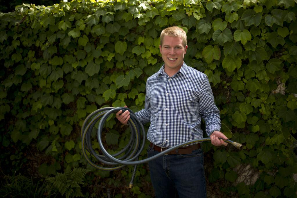 In this Friday, June 5, 2015, photo, Dan Estes, a Los Angeles real estate broker, pauses for photos with a water hose in Los Angeles. Estes has gone so far as to build his own water-shaming app that records the time and place where he sees waste. (AP Photo/Jae C. Hong)