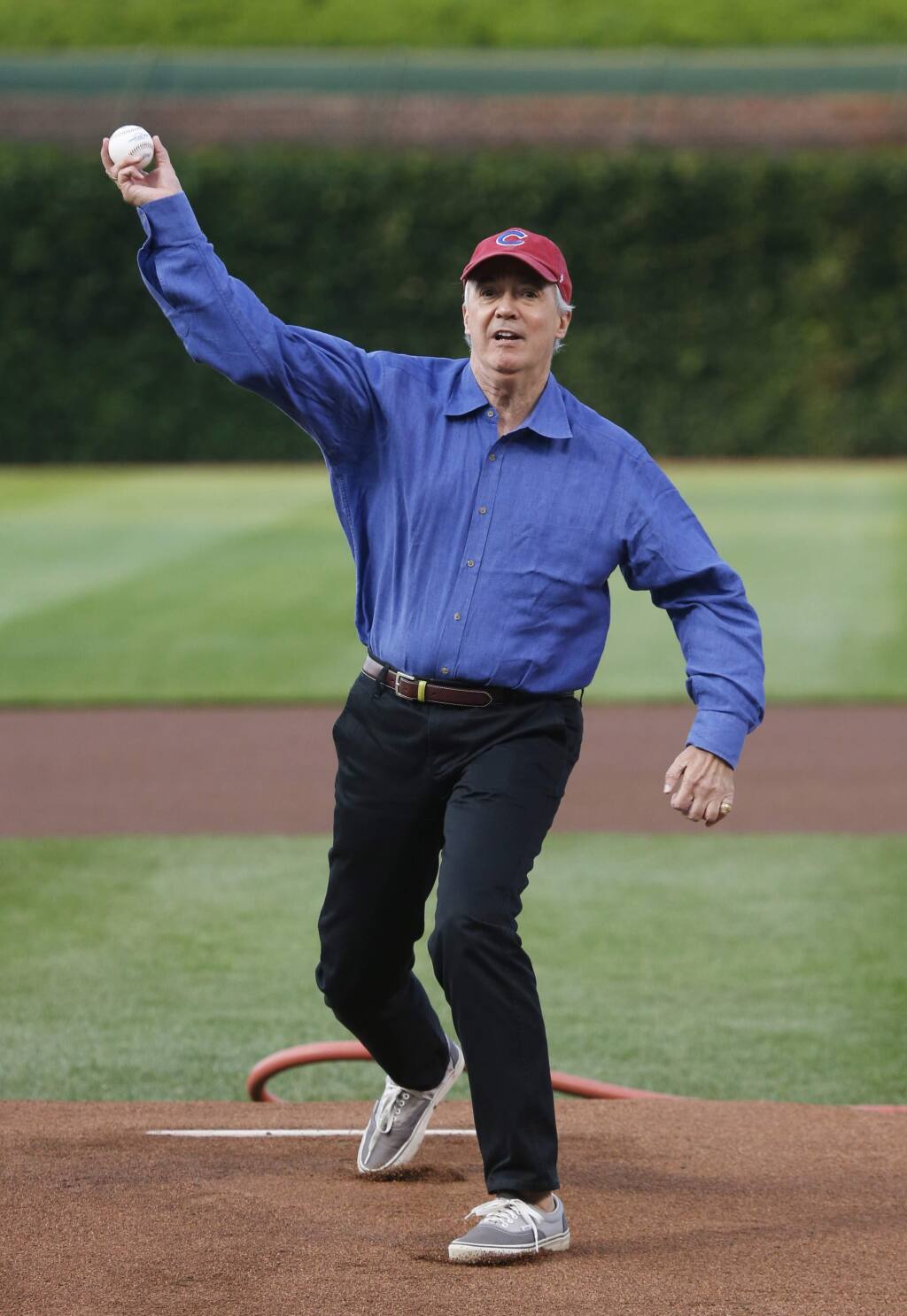 NPR reporter Scott Simon throws out a ceremonial first pitch before a baseball game between the Chicago Cubs and the Colorado Rockies Monday, July 28, 2014, in Chicago. (AP Photo/Charles Rex Arbogast)