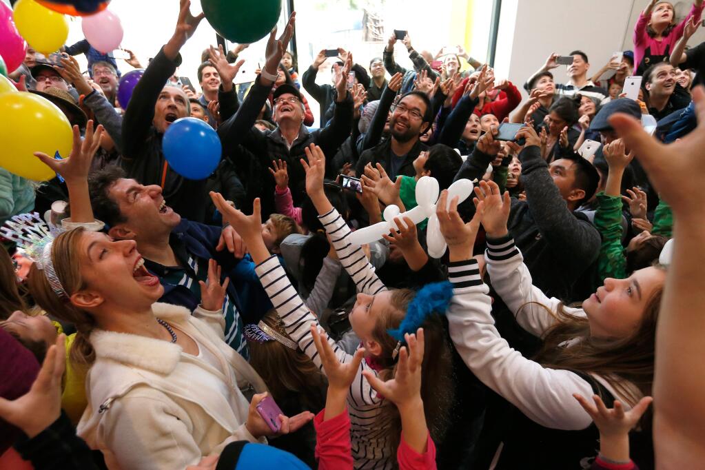 Parents Heather and David Gruenbaum, left, react and their daughters Rachel, 7, and Caroline, 10, center, reach up as balloons fall from the ceiling during the kids New Year's Eve celebration at the Charles M. Schulz Museum in Santa Rosa, California on Saturday, December 31, 2016. (Alvin Jornada / The Press Democrat)