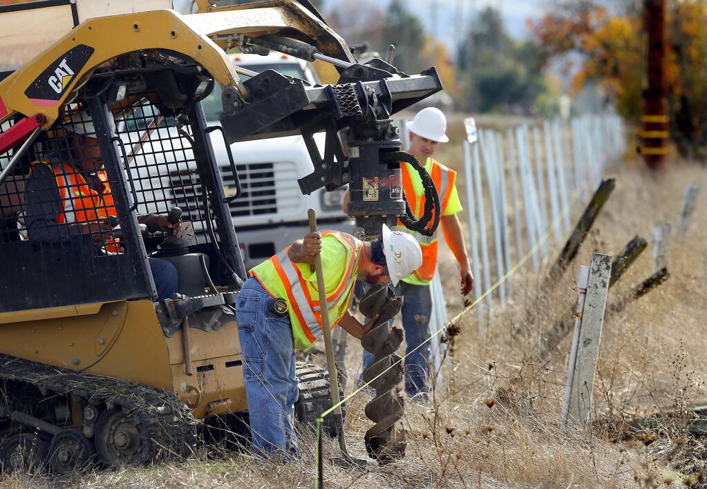 Hector Garcia, left, and Josh Cox dig holes for poles for a fence along the SMART tracks north of San Miguel Rd. in Santa rosa on Wednesday. (JOHN BURGESS / The Press Democrat)
