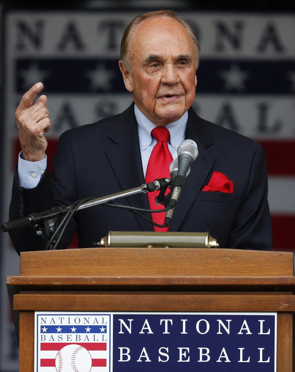 In this July 25, 2015, file photo, Dick Enberg speaks after receiving the Ford C. Frick Award during a ceremony at Doubleday Field in Cooperstown, N.Y. Enberg, the sportscaster who got his big break with UCLA basketball and went on to call Super Bowls, Olympics, Final Fours and Angels and Padres baseball games, died Thursday, Dec. 21, 2017. He was 82. (AP Photo/Mike Groll, File)