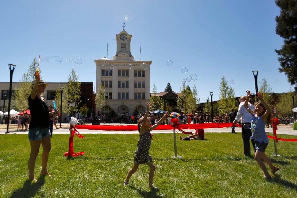 Dawn Sanz, left, floats bubbles in the breeze for her daughters Lily, 5, and Charlee, 8, during the celebration of the reunified Old Courthouse Square, in Santa Rosa, California, on Saturday, April 29, 2017. (Alvin Jornada / The Press Democrat)