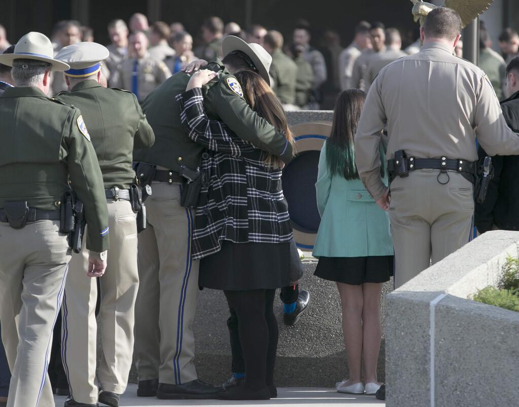 FILE - In this Dec. 27, 2017 file photo, Rosanna Camilleri, right, the wife of late California Highway Patrol Officer Andrew Camilleri Sr., hugs CHP officer Jonathan Velazquez following a bell ringing ceremony held at the highway patrol academy in West Sacramento, Calif. Authorities say a 22-year-old man who killed Camilleri Sr. on Christmas Eve after he slammed his car into the back of the officer's parked patrol car has been charged with second-degree murder. Alameda County District Attorney Nancy O'Malley on Tuesday, Jan. 2, 2018, identified Mohammed Ali, of Hayward, as the driver of a speeding Cadillac that drifted off Interstate 880 and crashed against Officer Andrew Camilleri's patrol SUV. (AP Photo/Rich Pedroncelli, File)