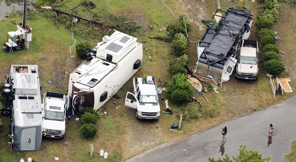 In this aerial photo people inspect damage at Cherrystone Family Camping & RV Resort in Northampton County, Va., Thursday, July 24, 2014, after a severe storm swept through the area. Softball-sized hail and rain toppled dozens of trees and flipped recreational vehicles at the campground Thursday, killing two people and injuring more than two dozen, officials said. (AP Photo/The Virginian-Pilot, L. Todd Spencer)