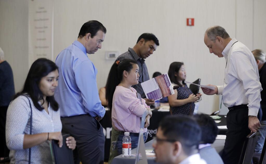 In this Thursday, Aug. 24, 2017, photo, Phil Wiggett, right, a recruiter with the Silicon Valley Community Foundation, looks at a resume during a job fair in San Jose, Calif. On Friday, Oct. 6, 2017, the U.S. government issues the September jobs report. (AP Photo/Marcio Jose Sanchez)