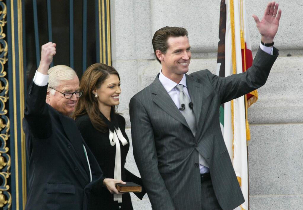 FILE - In this Jan. 8, 2004, file photo, newly sworn-in San Francisco Mayor Gavin Newsom, right, waves to supporters after taking the oath of office from his father, Judge William Newsom, left, at City Hall in San Francisco. At center is Kimberly Newsom, the mayor's wife. William Newsom III, a former California judge, has died at age 84. A Gavin Newsom spokesman says William Newsom died Wednesday morning, Dec. 12, 2018, at his home in San Francisco. (AP Photo/Jeff Chiu, File)