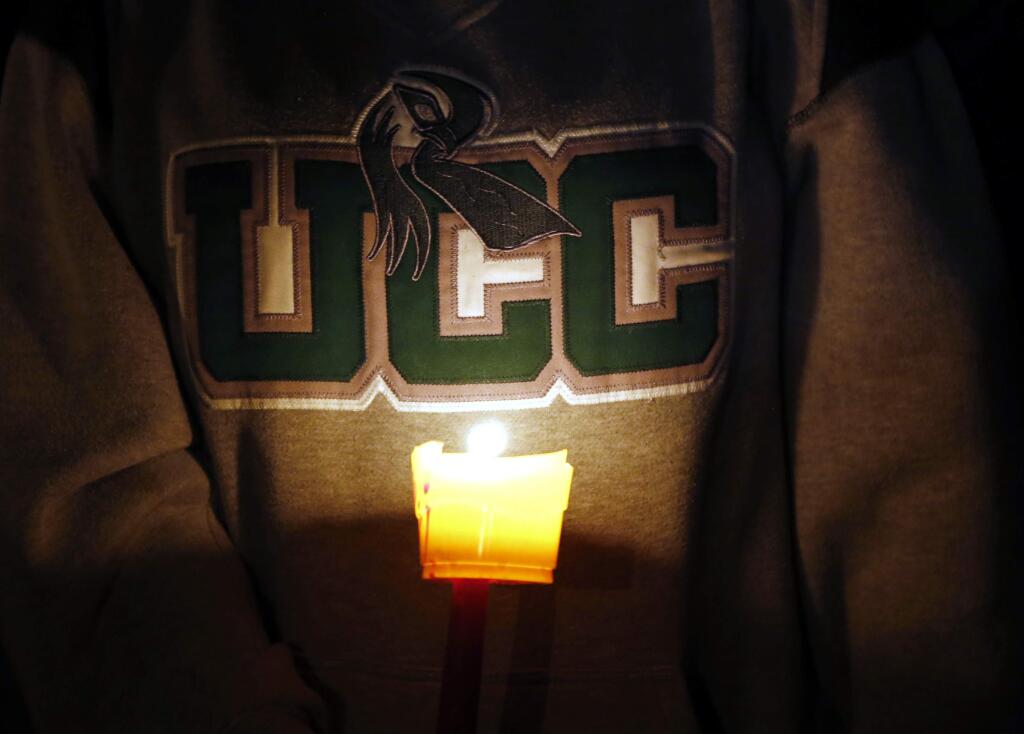 Diana Nicolay, a former employee of Umpqua Community College, wears a school sweatshirt during a candlelight vigil for those killed during a fatal shooting at the school Thursday, Oct. 1, 2015. (AP Photo/Rich Pedroncelli)