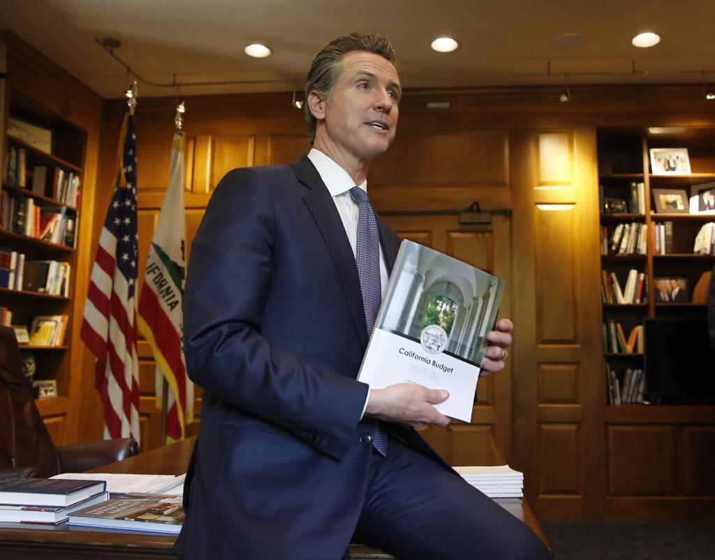 Gov. Gavin Newsom displays the 2019-2020 state budget book before he signed the $215 billion budget, in Sacramento, Calif., Thursday, June 27, 2019. This is Newsom's first state budget since becoming governor. (AP Photo/Rich Pedroncelli)