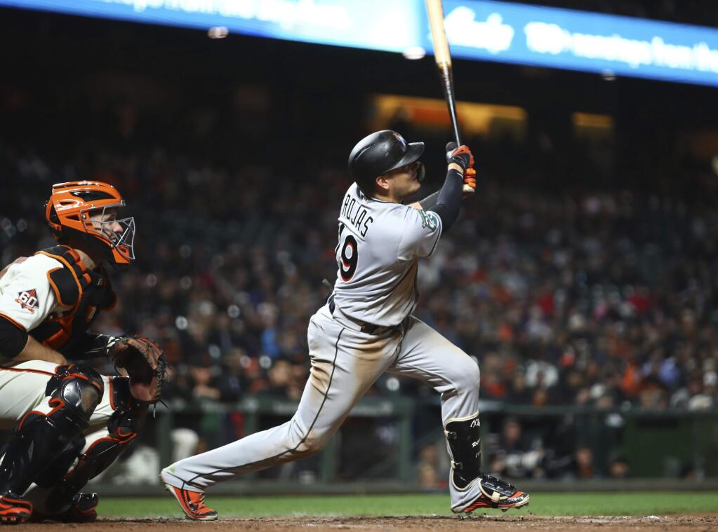 Miami Marlins' Miguel Rojas swings for an RBI single off San Francisco Giants' Hunter Strickland in the ninth inning of a baseball game Monday, June 18, 2018, in San Francisco. (AP Photo/Ben Margot)