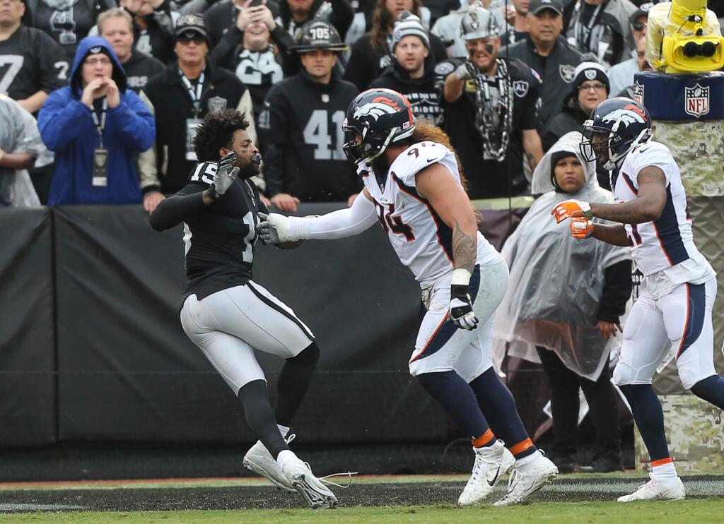 Denver Broncos tackle Domata Peko Sr. keeps Oakland Raiders wide receiver Michael Crabtree away from Denver Broncos cornerback Aqib Talib during their game in Oakland on Sunday, November 26, 2017. The Raiders defeated the Broncos 21-14.(Christopher Chung/ The Press Democrat)