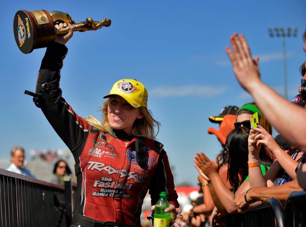 NHRA Funny Car champion Courtney Force raises her trophy in celebration as she walks to the winner's circle after the Sonoma Nationals at Sonoma Raceway on July 27, 2014. (Alvin Jornada / For The Press Democrat)