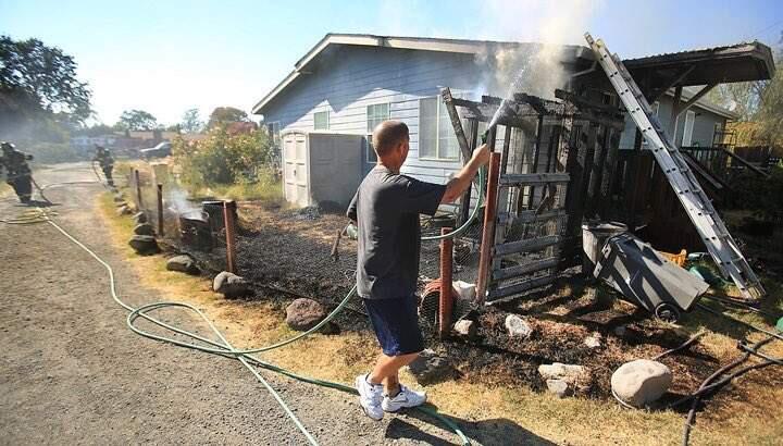 A neighbor helps battle a fire on Gerhard Drive in Santa Rosa on Wednesday, Aug. 24, 2016. (KENT PORTER / PRESS DEMOCRAT)