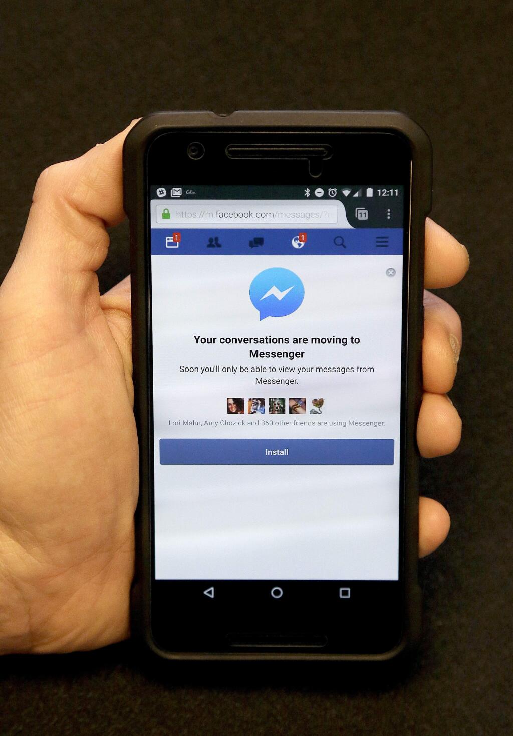 An Associated Press reporter holds a mobile phone showing the Facebook Messenger app installation page in San Francisco, Wednesday, July 27, 2016. Facebook is pushing more people to install its Messenger application, now by blocking people who want to send and receive messages via its mobile website instead of the app. (AP Photo/Jeff Chiu)