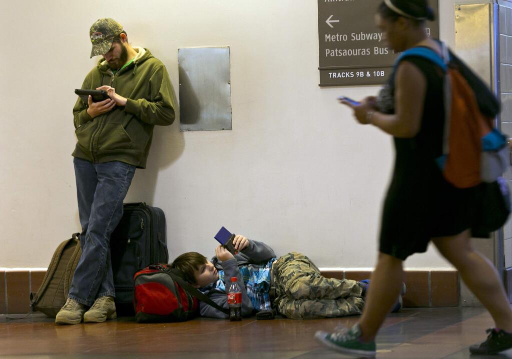 Passengers Morgan Griffin, 20, left, and his brother, Eric Crandell 12, browse their mobile devices as they await to board The Amtrak Pacific Surfliner train bound to Santa Barbara, Calif., at Union Station in Los Angeles, Wednesday, Nov. 26, 2014, a day before Thanksgiving. (AP Photo/Damian Dovarganes)