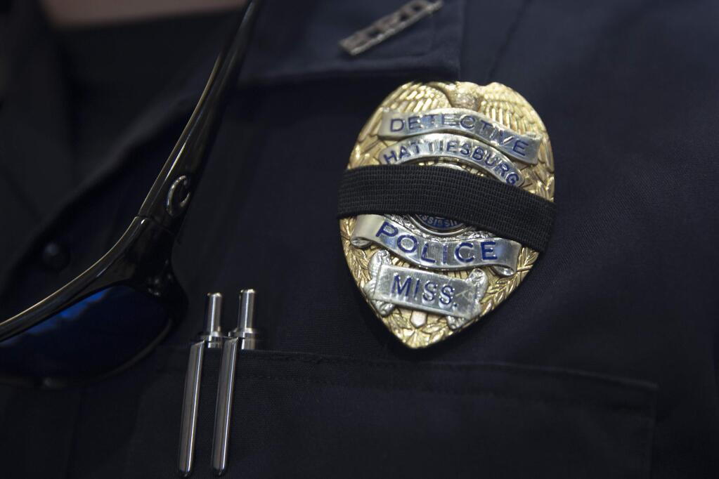 A Hattiesburg police detective wears a black band over his badge outside a memorial service for fellow Officers Benjamin Deen and Liquori Tate, who were shot last Saturday during a traffic stop. (EDMUND D. FOUNTAIN / New York Times)