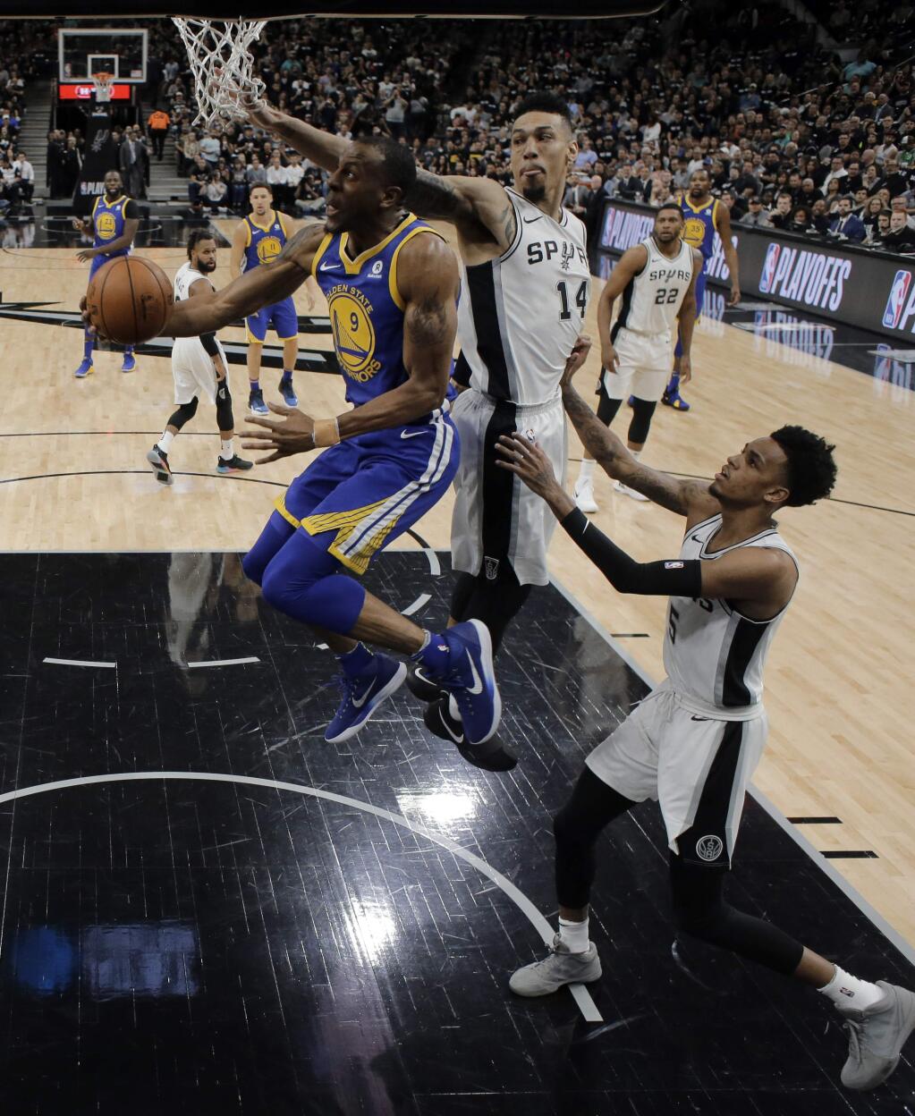 Golden State Warriors forward Andre Iguodala (9) goes up for a shot as San Antonio Spurs' Danny Green (14) and Dejounte Murray (5) defend during the first half of Game 3 of a first-round NBA basketball playoff series in San Antonio, Thursday, April 19, 2018. (AP Photo/Eric Gay)