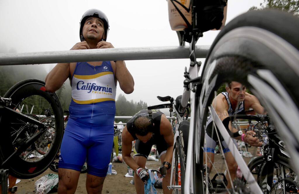 Jose Luis Montiel puts on his helmut as he transitions from the swimming to the cycling section of the the Ironman 70.3 Vineman Triathlon at Johnson's Beach in Guerneville, on Sunday, July 13, 2014. (BETH SCHLANKER/ The Press Democrat)