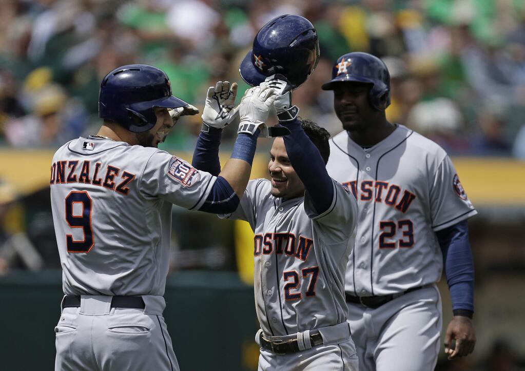 Houston Astros' Jose Altuve (27) celebrates with Marwin Gonzalez (9) and Chris Carter, right, after Altuve hit a three-run home run off Oakland Athletics' Kendall Graveman in the second inning of a game Saturday, April 25, 2015, in Oakland. (AP Photo/Ben Margot)