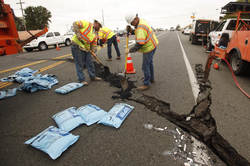 Caltrans employees fill the large crack where the road lifted on Sonoma Highway between Sonoma and Napa during a 6.0 earthquake that centered in American Canyon, Sunday, August 24, 2014. (Crista Jeremiason/The Press Democrat)