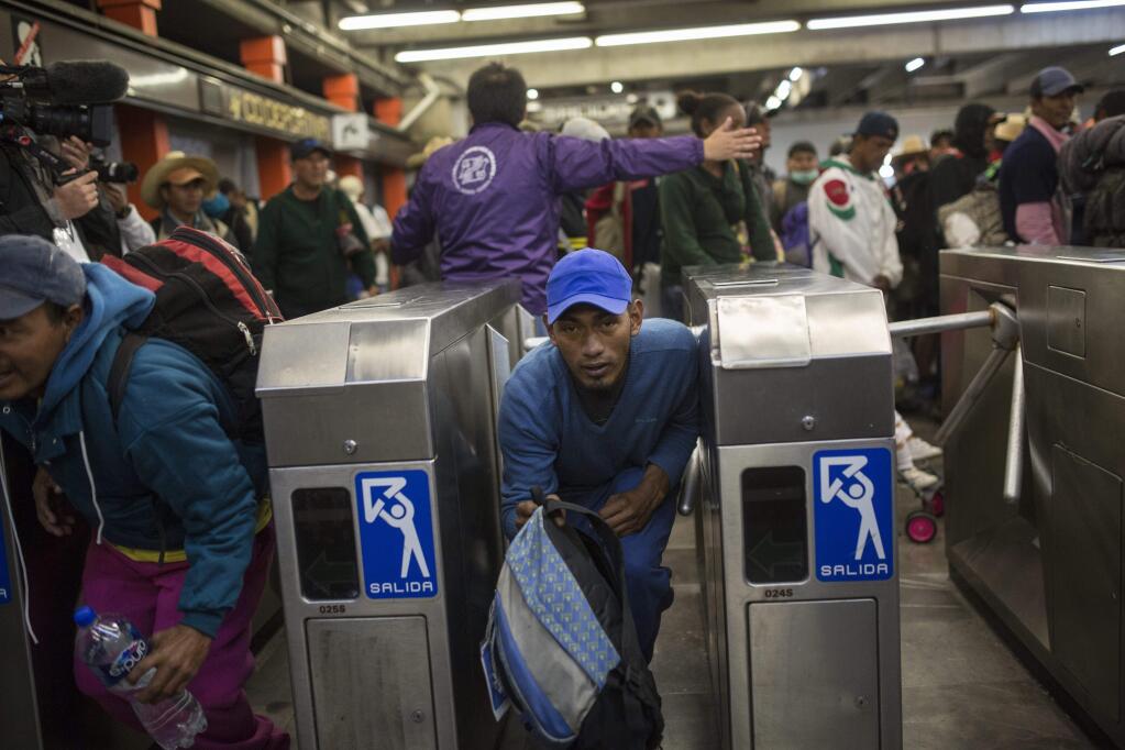 A Central American migrant bypasses a subway turnstile after leaving the temporary shelter at the Jesus Martinez stadium, in Mexico City, Friday, Nov. 9, 2018. About 500 Central American migrants headed out of Mexico City on Friday to embark on the longest and most dangerous leg of their journey to the U.S. border, while thousands more were waiting one day more at the stadium. (AP Photo/Rodrigo Abd)