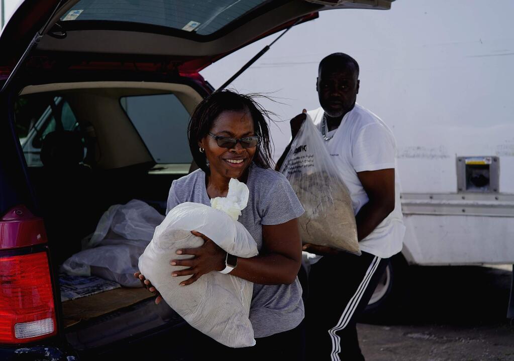 Yolande Rolle carries sandbags to place at her shop's doorstep as she prepares for the arrival of Hurricane Dorian in Freeport on Grand Bahama, Bahamas, Sunday, Sept. 1, 2019. Hurricane Dorian intensified yet again Sunday as it closed in on the northern Bahamas, threatening to batter islands with Category 5-strength winds, pounding waves and torrential rain. (AP Photo/Ramon Espinosa)