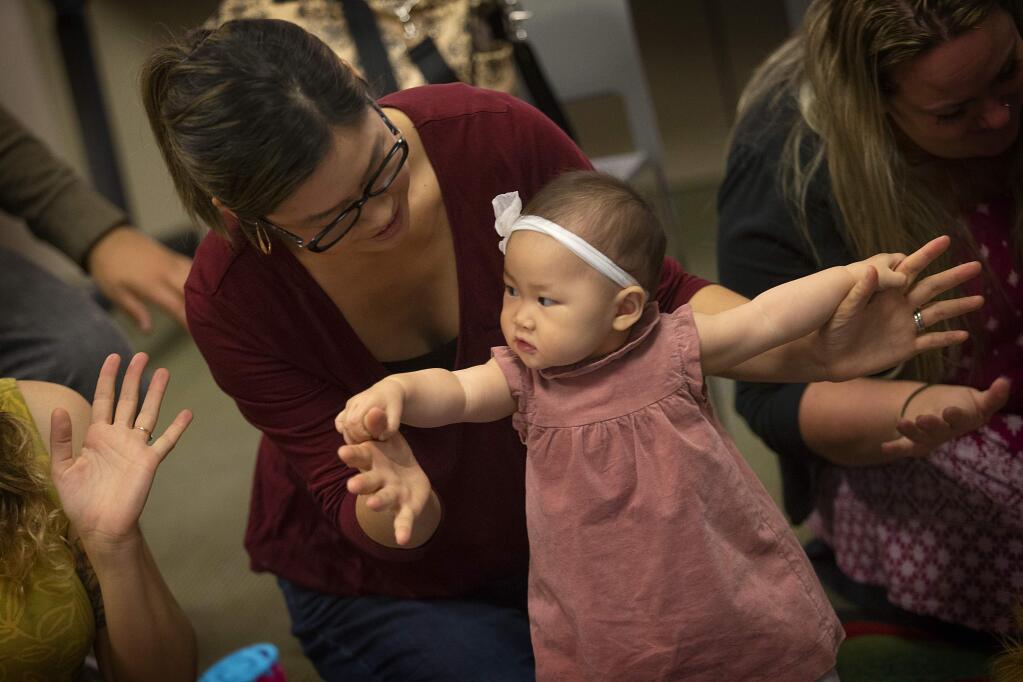 Christina Umehara sings and plays with her 9-month-old daughter Ellie during reading time at the Sebastopol library on Friday. The pair are participants in a UC Davis study aimed at assessing the health impacts of smoke from the October wildfires on unborn babies. (photo by John Burgess/The Press Democrat)