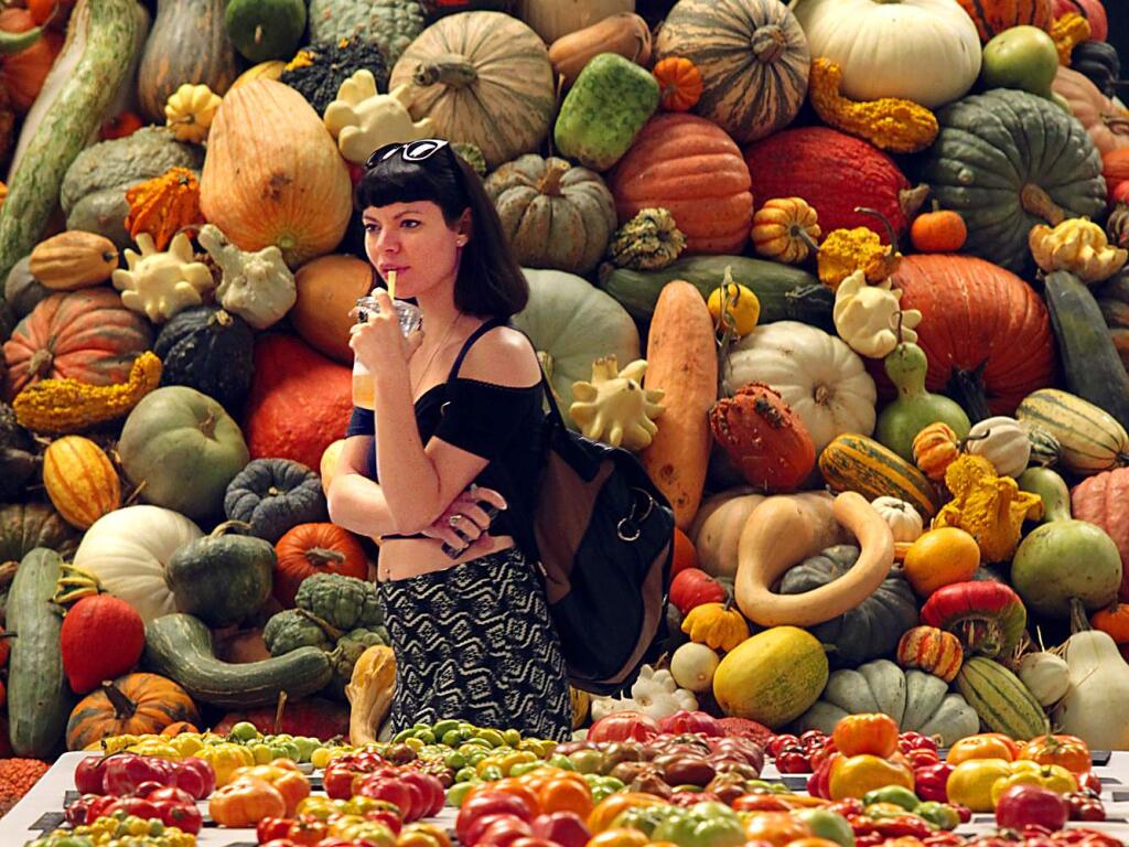Monica Schaefer of San Francisco walks by a giant pile of gourds and a table filled with heirloom tomatoes at the National Heirloom Exposition at the Sonoma Fairgrounds on Tuesday, September 9, 2014.