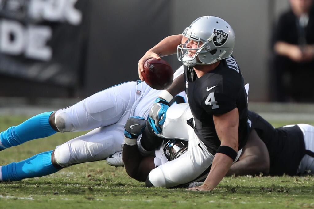Oakland Raiders quarterback Derek Carr grimaces as he is sacked by the Carolina Panthers during their game in Oakland on Sunday, November 27, 2016. The Raiders defeated the Panthers 35-32.(Christopher Chung/ The Press Democrat)
