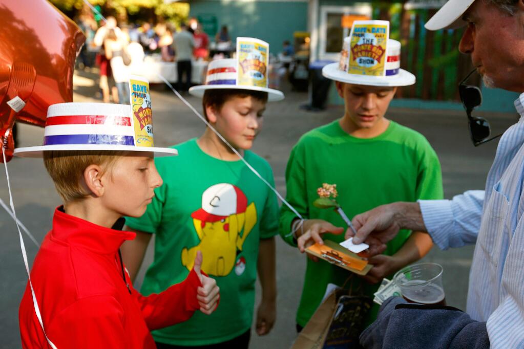 Volunteers Jack Donnell, 12, left, Hunter Winkler, 11, and Jack Kimmel, 12, sell raffle tickets to Jim Heneghan of Bodega Bay during the Monte Rio Variety Show in Monte Rio, California, on Thursday, July 27, 2017. (Alvin Jornada / The Press Democrat)