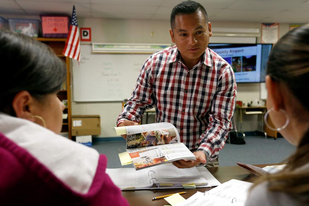 Instructor Neil Pacheco answers questions for Rosa Lopez, left, and Nereyda Grajeda about the Sonoma County Visitors Guide they are studying during an adult education Essential Hospitality Skills class in Petaluma, California on Wednesday, June 15, 2016. (Alvin Jornada / The Press Democrat)