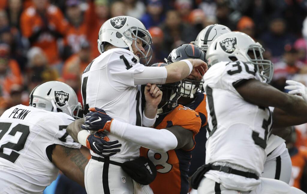 Oakland Raiders quarterback Matt McGloin, center, is hit by Denver Broncos outside linebacker Shaquil Barrett after McGloin got a pass off during the first half of an NFL football game, Sunday, Jan. 1, 2017, in Denver. (AP Photo/Joe Mahoney)