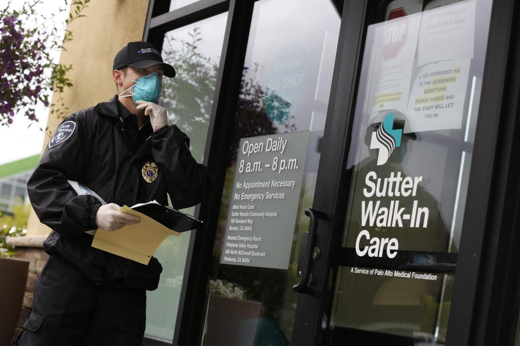 Robert Fletcher, a security guard with Allied Universal, waits with a questionnaire to screen patients about their symptoms before they can enter Sutter Walk-In Care in Petaluma, California on Wednesday, March 18, 2020. (BETH SCHLANKER/The Press Democrat)