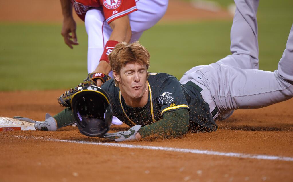Oakland Athletics' Mark Canha, right, dives back to first under the tag of Los Angeles Angels first baseman Albert Pujols during the fifth inning of a game, Tuesday, April 21, 2015, in Los Angeles. (AP Photo/Mark J. Terrill)