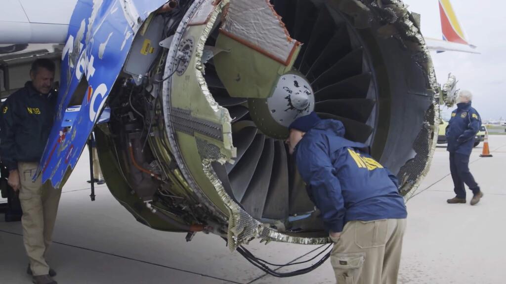 In this Tuesday, April 17, 2018 frame from video, a National Transportation Safety Board investigator examines damage to the engine of the Southwest Airlines plane that made an emergency landing at Philadelphia International Airport in Philadelphia. A preliminary examination of the blown jet engine of the Southwest Airlines plane that set off a terrifying chain of events and left a businesswoman hanging half outside a shattered window showed evidence of 'metal fatigue,' according to the National Transportation Safety Board. (NTSB via AP)