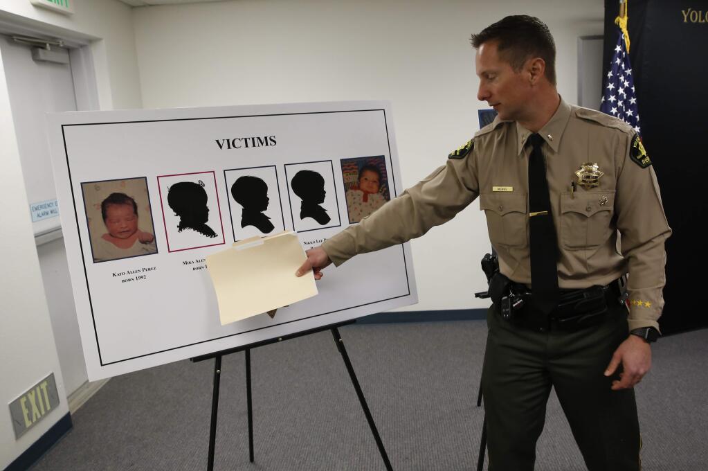 Lieutenant Matthew Davis of the Yolo County Sheriff's Department gestures to the images of five infants believed to be killed by their father, during a news conference in Woodland, Calif., Monday, Jan. 27, 2020. Paul Perez, 57, has been arrested in the decades-old killings of five of his infant children, a case the sheriff said had haunted his agency for years, the Yolo County Sheriff's Office said Monday, Jan. 27, 2020. (AP Photo/Rich Pedroncelli)