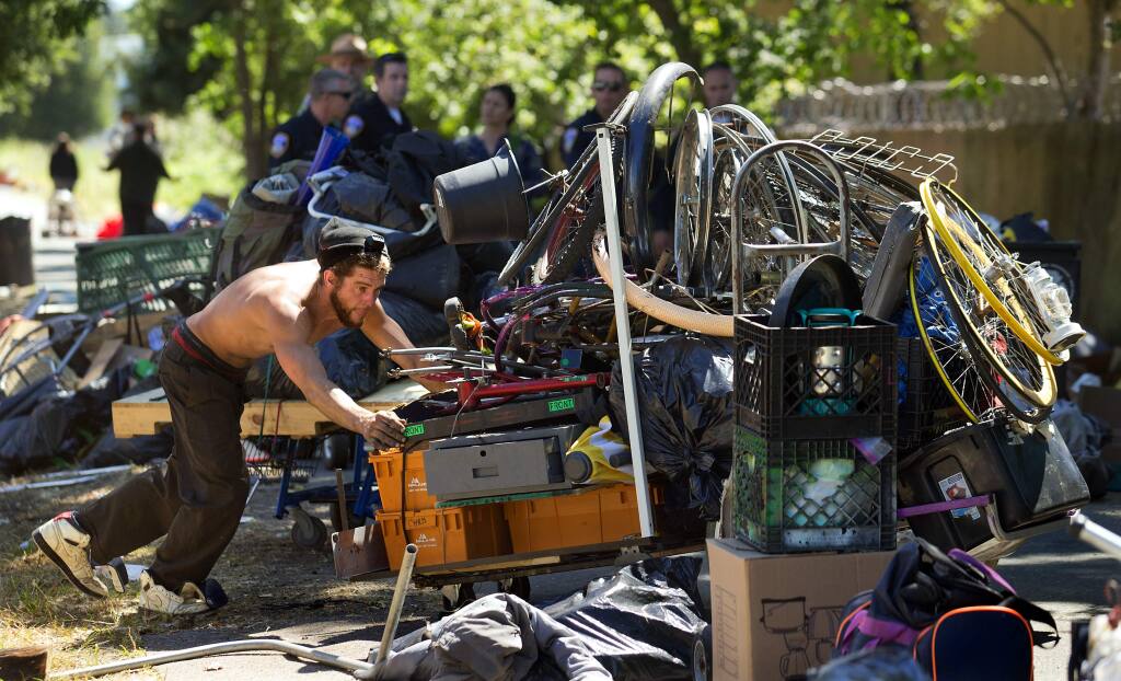 A homeless man tries to push a cobbled-together cart filled with his possession as Santa Rosa police officers closed a large encampment along the Joe Rodota Trail west of Dutton Ave. in Santa Rosa. (photo by John Burgess/The Press Democrat)