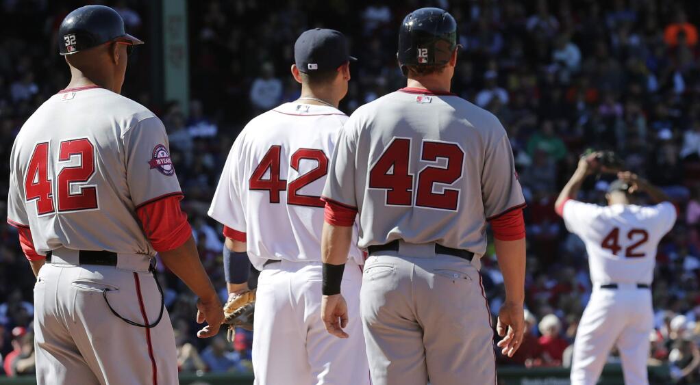 With all players and coaches wearing #42 in remembrance of Jackie Robinson, Boston Red Sox relief pitcher Anthony Varvaro, right, sets to pitch during a baseball game at Fenway Park in Boston, Wednesday, April 15, 2015. Robinson broke Major League Baseball's color barrier on April 15, 1947, taking the field as the first African-American player for the Brooklyn Dodgers. From left are Nationals first base coach Tony Tarasco, Red Sox first baseman Mike Napoli, Nationals base runner Tyler Moore and Varvaro. (AP Photo/Charles Krupa)