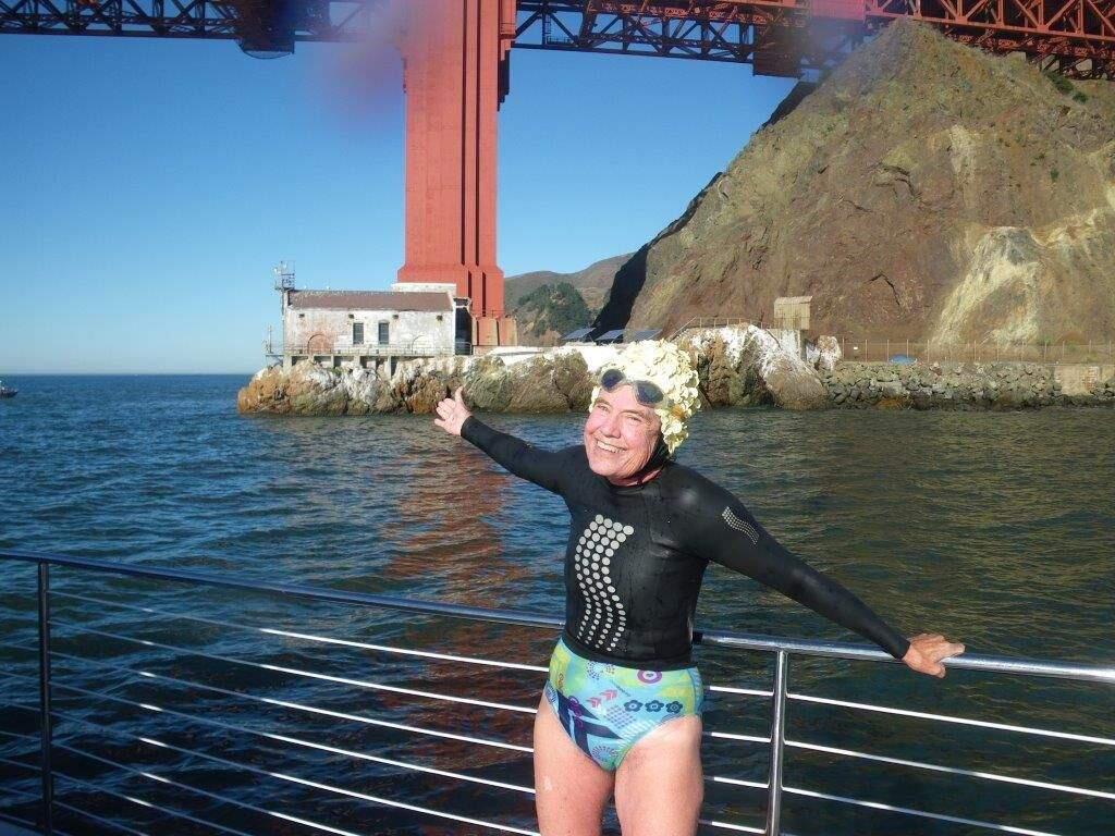 MARY BLAKESLEE PHOTO Petaluma's Kathie Hewko celebrates on the Marin side of the Golden Gate after completing her 92nd Golden Gate Bridge swim just days after her 70th birthday.