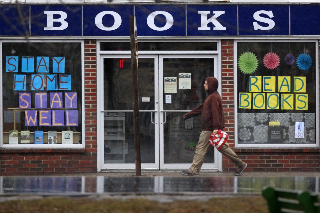 Signs in a bookstore window in Brunswick, Maine encourage residents to stay home. (ROBERT F. BUKATY / Associated Press)