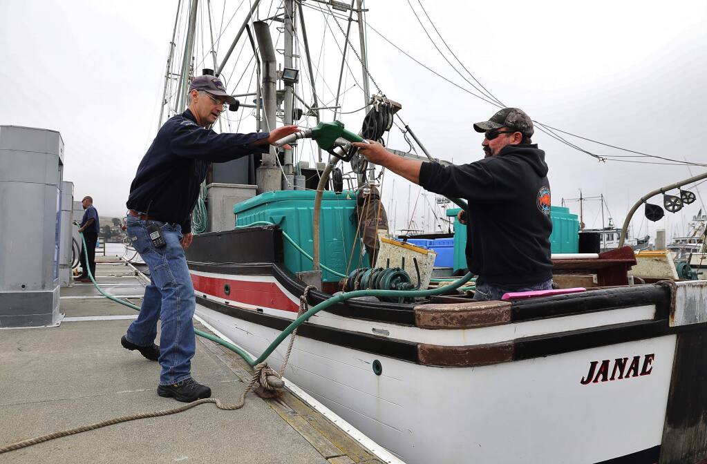 Tom Graham, right, hands a gas pump to Spud Point Marina attendant John Keller, after fueling up the 'Janae', in Bodega Bay on Monday, July 31, 2017. Graham and his brother, Jeff Graham, are heading out for the start of the commercial salmon fishing season.(Christopher Chung/ The Press Democrat)