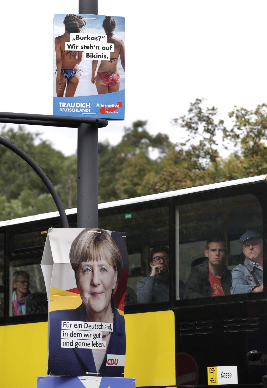 FILE - In this Thursday, Sept. 7, 2017 file photo an election campaign poster of the German AfD (Alternative for Germany) party is attached above an election poster of Chancellor Angela Merkel to a streetlamp close to the party headquarters of the German Christian Democrats in Berlin. Polls show four parties competing for third place at Sunday's election, with support between 7 and 12 percent: the Free Democrats, who look set to return to parliament after a four-year absence; the Greens, the Left Party and the AfD. (AP Photo/Michael Sohn, file)