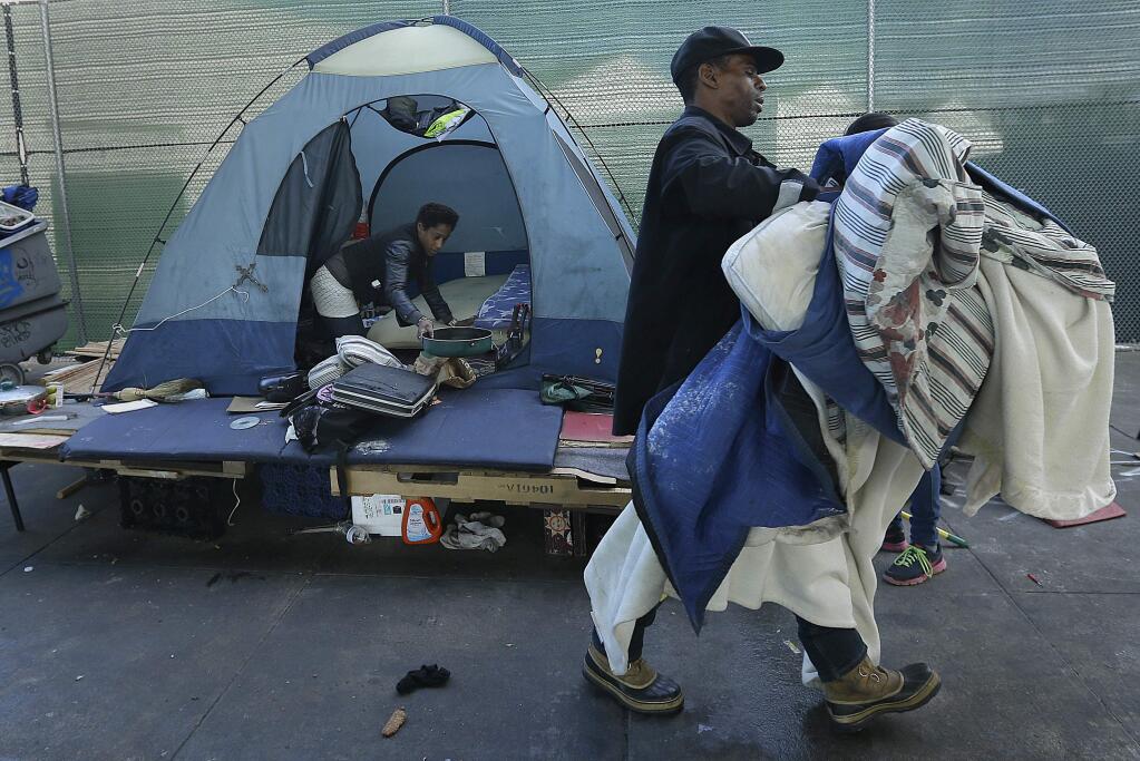 A homeless couple gather their belongings in San Francisco, Tuesday, March 1, 2016. Crews in San Francisco on Tuesday began sweeping out a homeless camp under the city's Central Freeway that was declared a health hazard and for months has been a source of irritation for neighbors and nearby businesses. (AP Photo/Ben Margot)