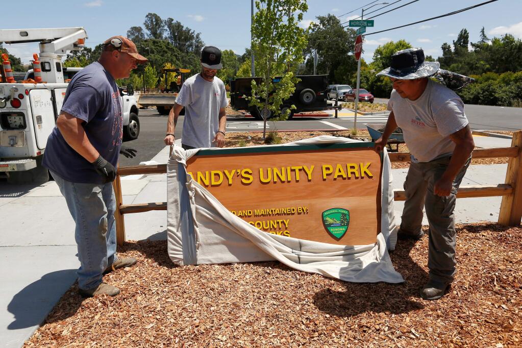 Dave Bailey, left, of Healdsburg Signs, with Thomas Rogers and Miguel Reyes of Reyes Sign Erection unwrap the official Sonoma County Parks sign for Andy's Unity Park, in Santa Rosa, California, on Thursday, May 31, 2018. (Alvin Jornada / The Press Democrat)