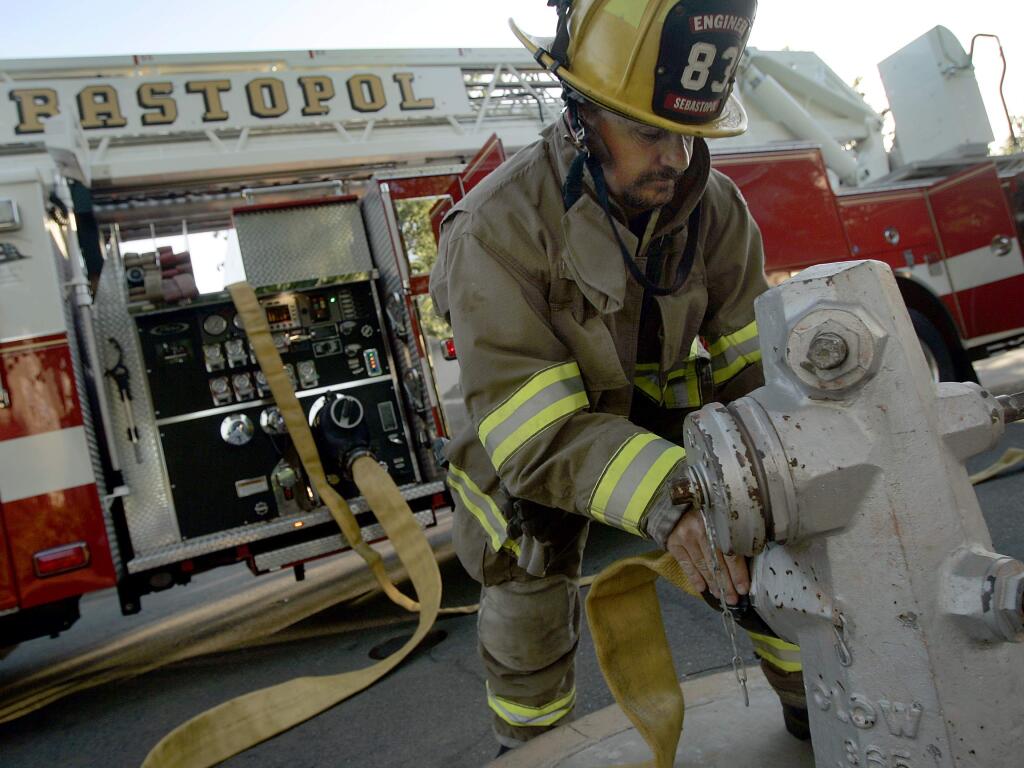 Sebastopol firefighter Sean MacRae hooks up to a hydrant during a training drill in Sebastopol, Thursday July 24, 2009. MacRae, like the rest of the Sebastopol department is a volunteer, except for the fire chief. (Kent Porter / Press Democrat) 2009