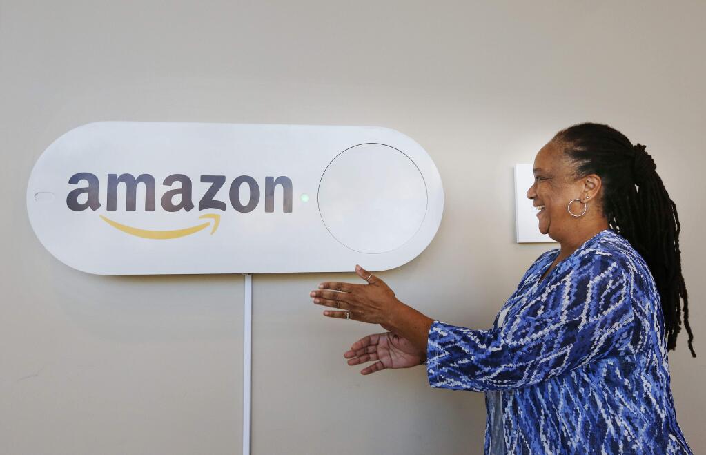 In this Monday, Oct. 16, 2017, photo, Migdawlaw Yisrael, a staffer at the University of Alabama at Birmingham's Hill Student Center, pushes a large Amazon Dash button, in Birmingham, Ala. The large Dash buttons are part of the city's campaign to lure Amazon's second headquarters to Birmingham. (AP Photo/Brynn Anderson)