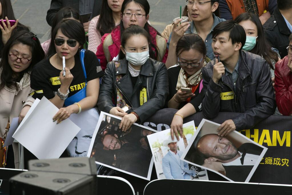 Fans wait with posters of actor Jason Statham before a promotional event for the movie 'Furious 7' ahead of its April release in Beijing, Thursday, March 26, 2015. (AP Photo/Mark Schiefelbein)