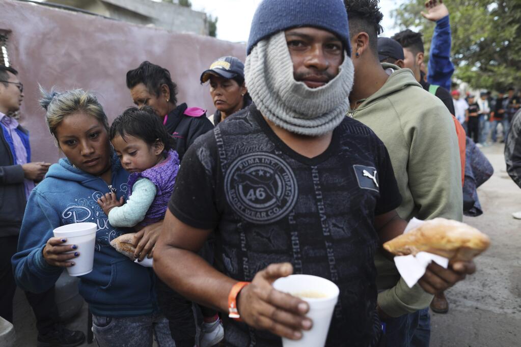 Central American migrants, part of the caravan hoping to reach the U.S. border, have breakfast outside a temporary shelter in Tijuana, Mexico, Friday, Nov. 16, 2018. As thousands of migrants of asylum-seekers converge on the doorstep of the United States, what they won't find are armed American soldiers standing guard, that's because U.S. military troops are prohibited from carrying out law enforcement duties. (AP Photo/Rodrigo Abd)